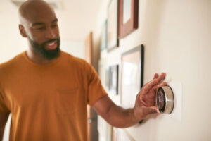 homeowner setting temperature on thermostat