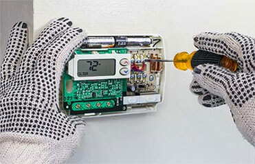 A thermostat being repaired, on of many HVAC repair services offered by Aaron Services.