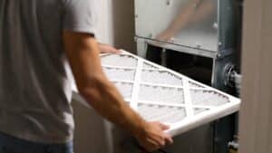 a homeowner changes his filter as part of ac troubleshooting process