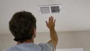 a homeowner holds his hand to the air supply wondering why is my air conditioner not cooling