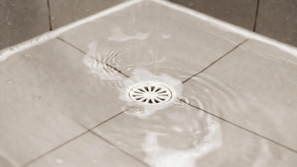 a shower drain clogged with hair and soap scum