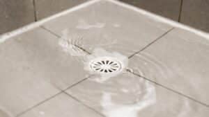 a shower drain clogged with hair and soap scum