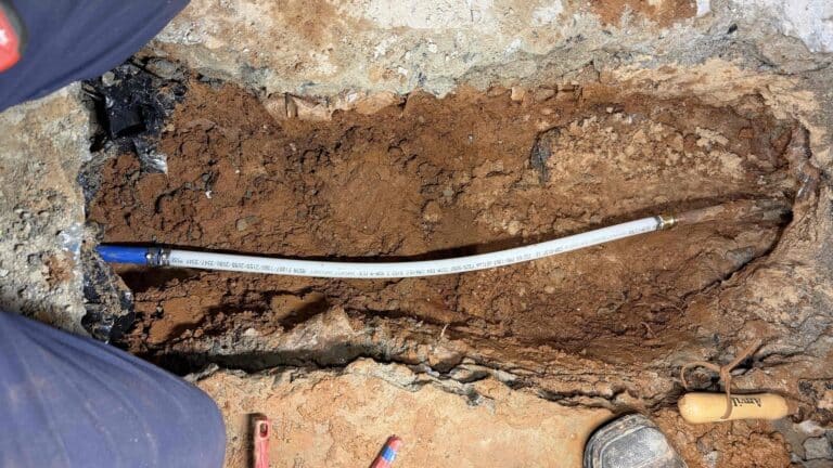 Slab leak repair in progress in Lawrenceville home with exposed pipe under concrete slab