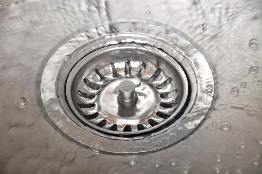 Close-up of a stainless steel kitchen sink drain with water