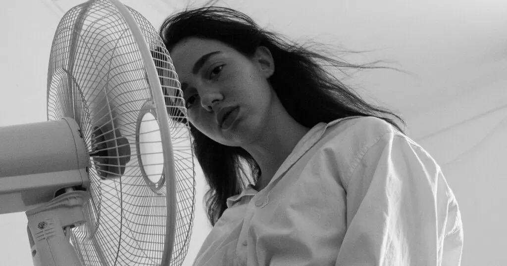 woman cooling off with fan